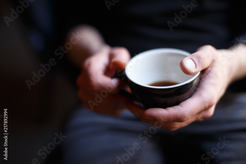 Man holds cup of black coffee in his hands