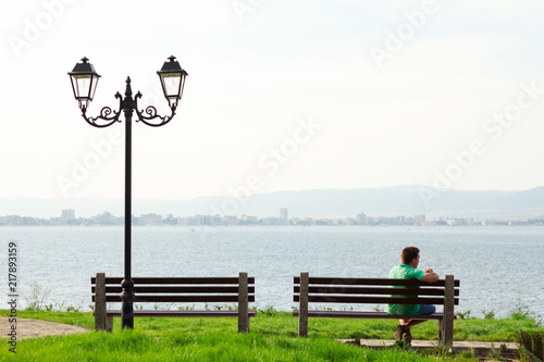man sitting back on a bench with a view on sea
