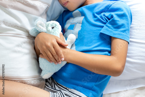 Little boy sleeping in bed holding his bunny robbit. photo