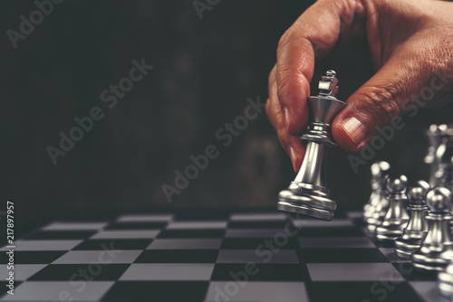 Chess game, chess player makes a move silver king step forward. Chess pieces on board. Man plays chess and makes the first move a pawn. Chessman playing chess. Business planning and strategy concept.