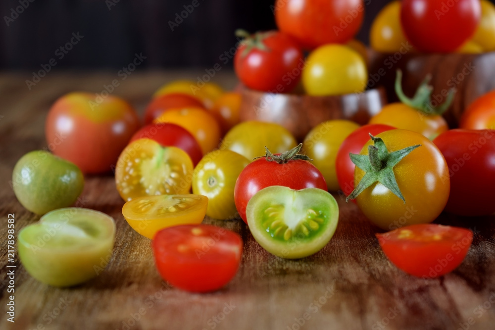 Assortment of multicoloured whole and cut tomatoes on a wooden table Assortment of multicoloured whole and cut tomatoes on a wooden table