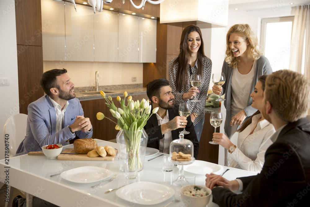 Young friends having dinner at home and toasting with white wine Young friends having dinner at home and toasting with white wine