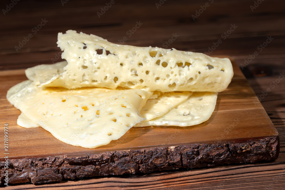 holes cheese sliced on wooden background
