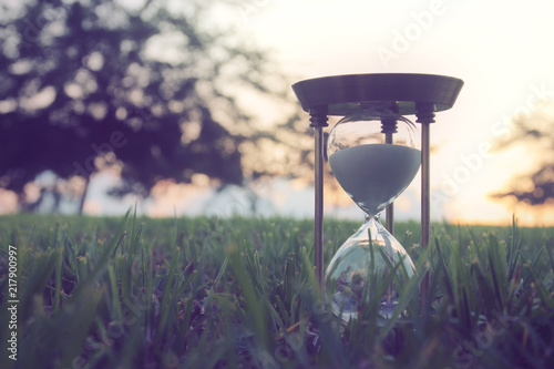 Hourglass in the grass time during sunset. vintage style.