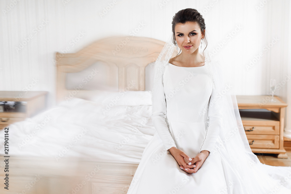 Portrait of charming bride sitting on the bed in a hotel room Portrait of charming bride sitting on the bed in a hotel room