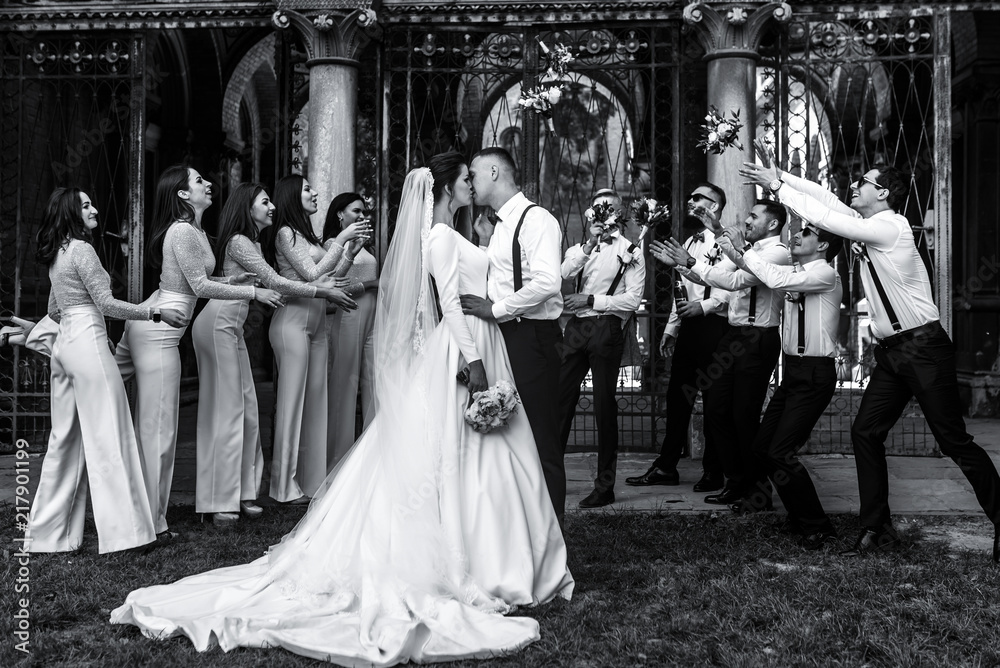 Friends have fun on the background while newlyweds kiss before them