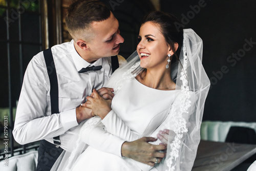 Kissing newlyweds have fun posing in the room