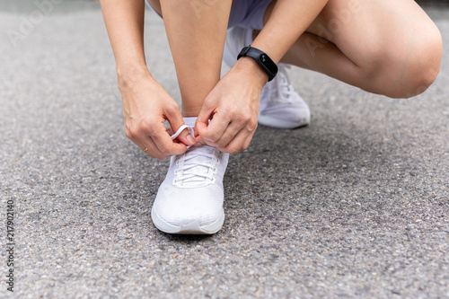 Asian woman tying shoelaces getting ready for running exercise in the park.