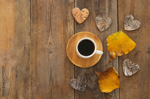 top view image of coffee cup over wooden table and dry autumn leaves.
