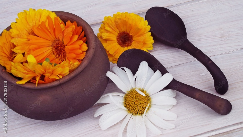 Medicinal herbs calendula and chamomile in a pot on a wooden background. Medicinal herbs calendula and chamomile in a pot on a wooden background.