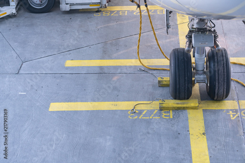  Landing Gear of a modern airliner - tires of a plane - close up shot. Wheels of airplane with aircraft chocks and chains on the landing field.