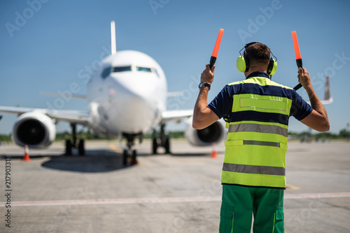 Welcome home. Back view of aviation marshaller directing aircraft landing photo