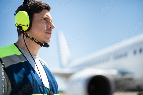 Looking for best solution. Side view of confident man looking into the distance. Passenger plane on blurred background