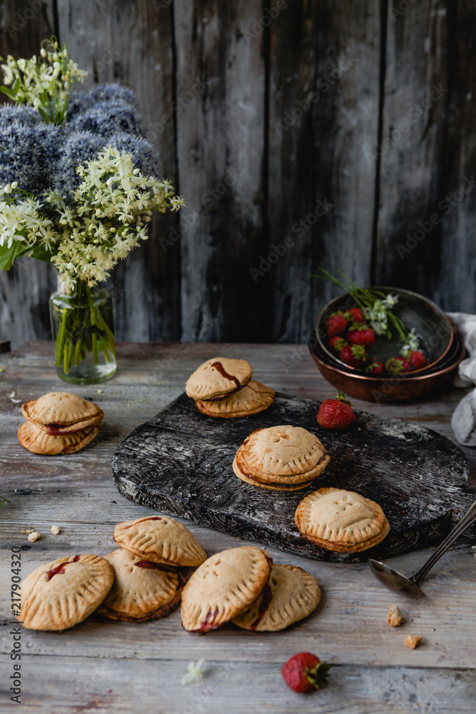 delicious cookies with strawberries on wooden table delicious cookies with strawberries on wooden table