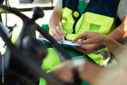 Taking notes. Close up of male hands writing down data on clipboard. Man holding pen while his colleague pointing at the document