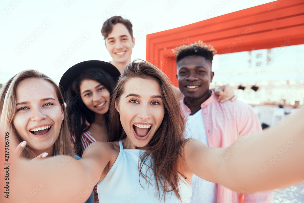 Glad females and cheerful males doing selfie while looking at camera. Optimistic comrades resting together concept Glad females and cheerful males doing selfie while looking at camera. Optimistic comrades resting together concept