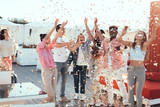 Satisfied ladies and beaming males catching confetti while having fun during funny party outdoor