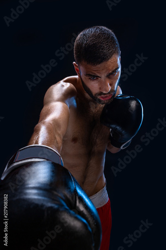 Man is hitting an opponent. Focused fighter with naked torso and boxing gloves looking at the camera. Win. © nazarovsergey
