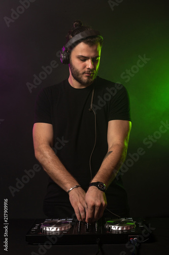 DJ playing music at mixer on colorful foggy background