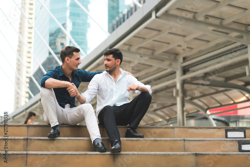 Two friend sitting down on stairs shaking hands. Businessmen very happy after success project. concept of business marketing, negotiation, compliment and management.