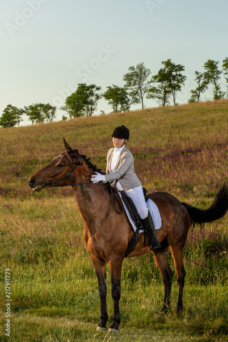 Young woman rider with her horse in evening sunset light. Outdoor photography in lifestyle mood