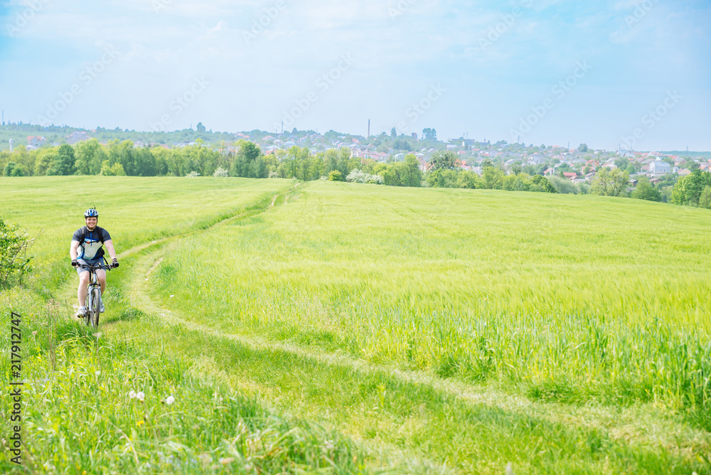 man riding bicycle by trail in green barley field. copy space man riding bicycle by trail in green barley field. copy space
