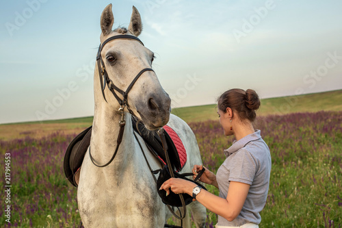 Beautiful young girl smile at her horse dressing uniform competition: outdoors portrait on sunset