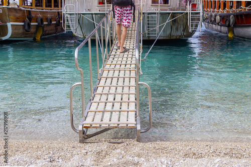 The legs of a man climb the ship along the ladder