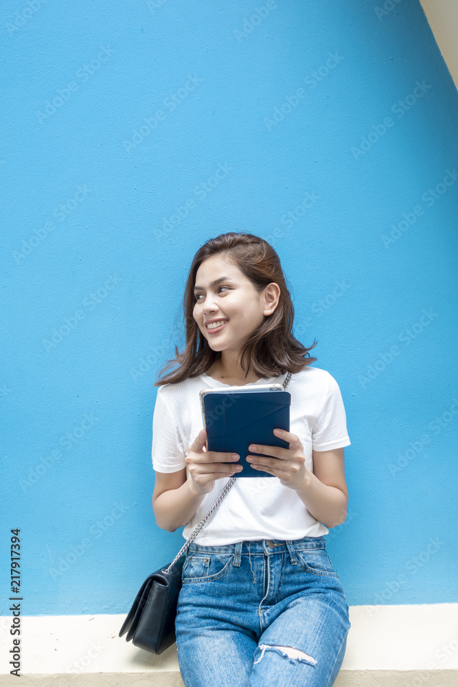 portrait of beautiful university student is smiling on blue wall background