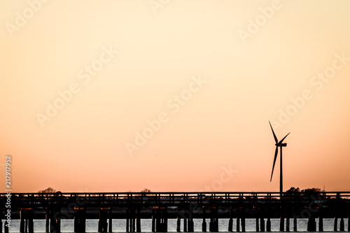 wind turbine by pier at sunset