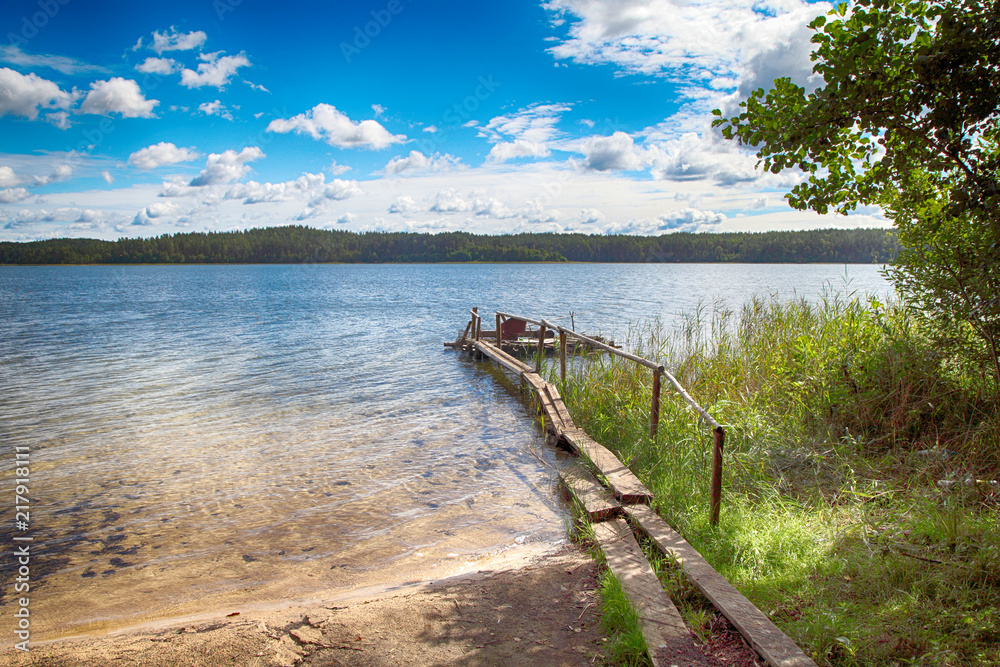 Beautiful summer landscape. Lake with a bridge against a blue sky with clouds.