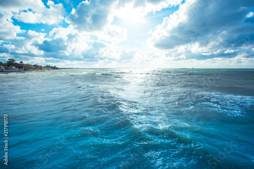 beach and sea with waves under the sunny cloudy sky