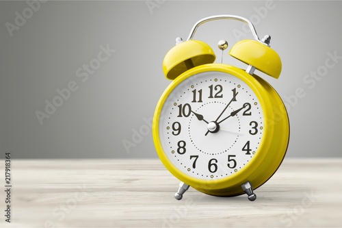 Yellow retro alarm clock on wooden table