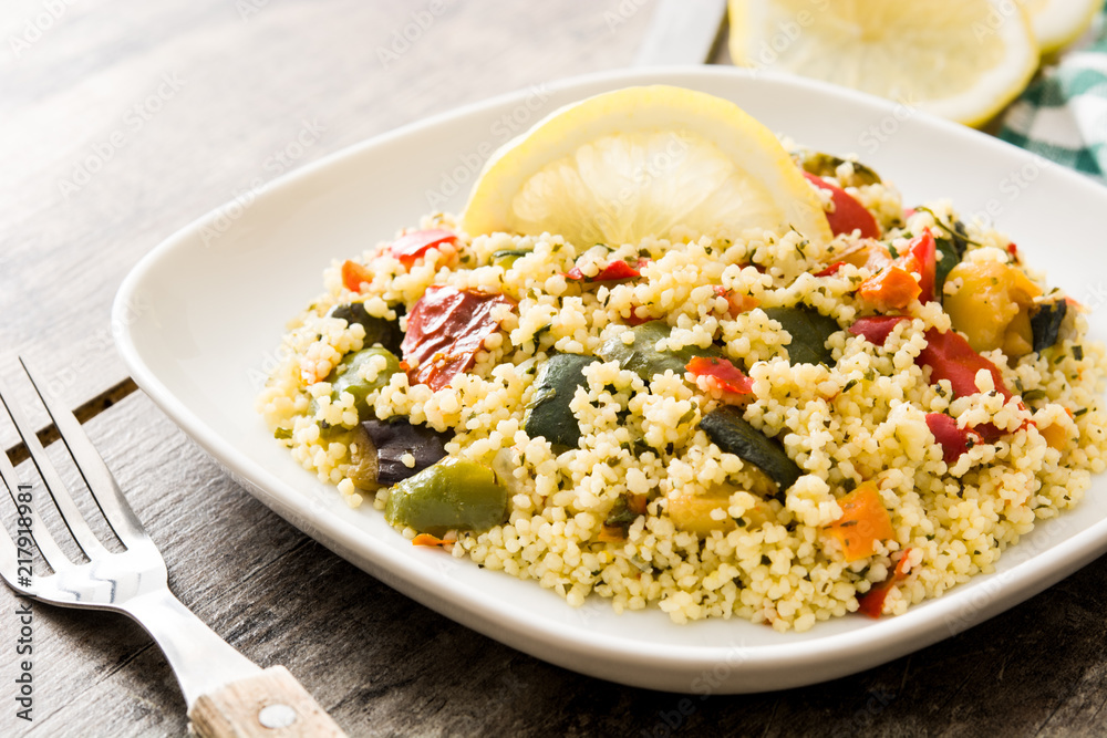 Couscous with vegetables in plate on wooden table Couscous with vegetables in plate on wooden table