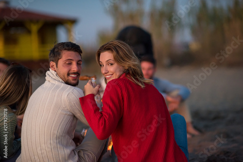 Couple enjoying with friends at sunset on the beach