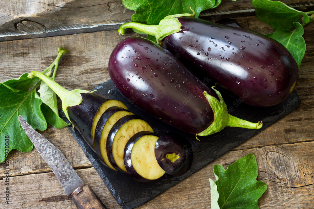Fresh healthy raw Purple Eggplant on a kitchen wooden table. The concept of Diet menu. - obrazy, fototapety, plakaty 