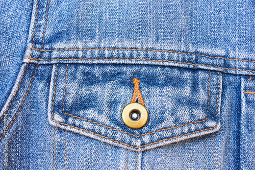 Dark blue jeans texture for design. Part of the cyan jeans jacket with pocket and a metallic button close-up. photo