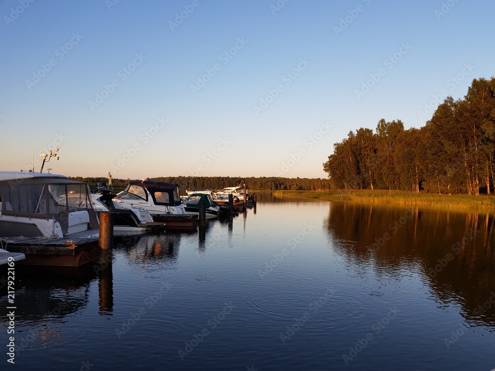 boats and yachts on the dock on the river at sunset