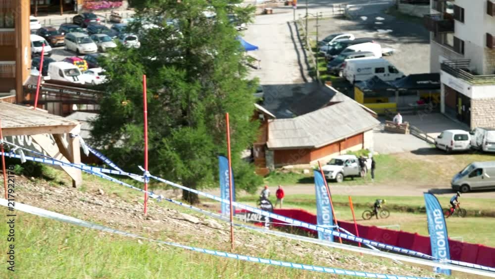 Mountain biker riding off of a wooden ramp with town below during the Downhill French Championship. Mountain biker riding off of a wooden ramp with town below during the Downhill French Championship.