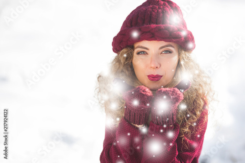 Portrait of young cheerful woman blowing snow into camera photo