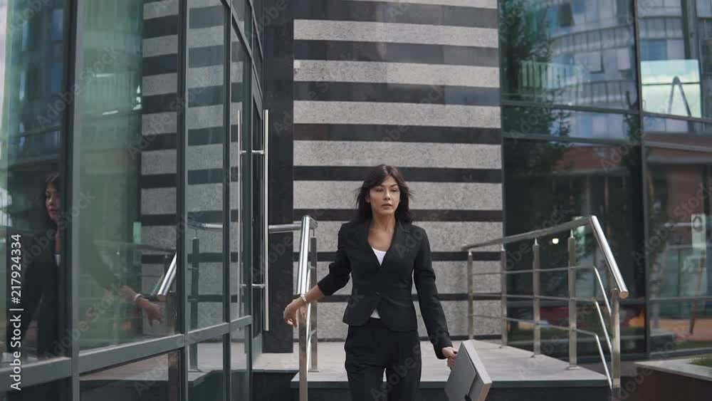 attractive business woman exits from a modern business center and confidently walks down the street attractive business woman exits from a modern business center and confidently walks down the street