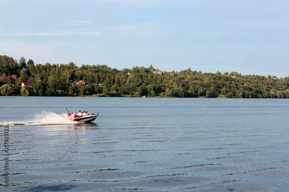Obraz premium sunny day on the river. Lovers ride in a boat on a lake during a beautiful sunset. Happy couple woman and man together relaxing on the water. The beautiful nature around.