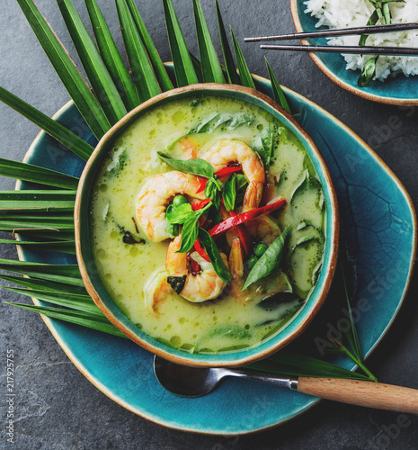 THAI SHRIMPS GREEN CURRY. Thailand tradition green curry soup with shrimps prawns and coconut milk. Green Curry in blue plate on gray background.