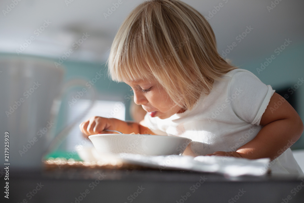 A young girl eating breakfast. 