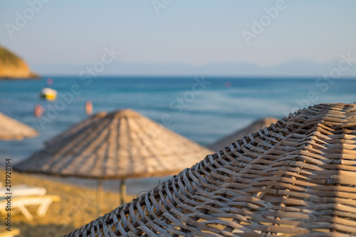 Straw umbrellas on the beach with sea and sky in the closeup background. photo