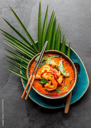 THAI SHRIMPS RED CURRY. Thailand Thai tradition red curry soup with shrimps prawns and coconut milk. Panaeng Curry in blue plate on gray background