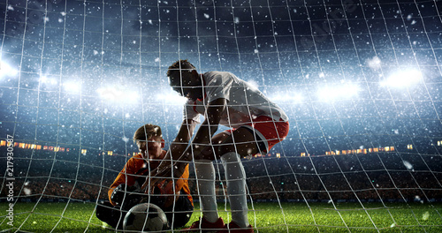 Attacker scores a goal and celebrates victory on a professional soccer stadium while it s snowing.