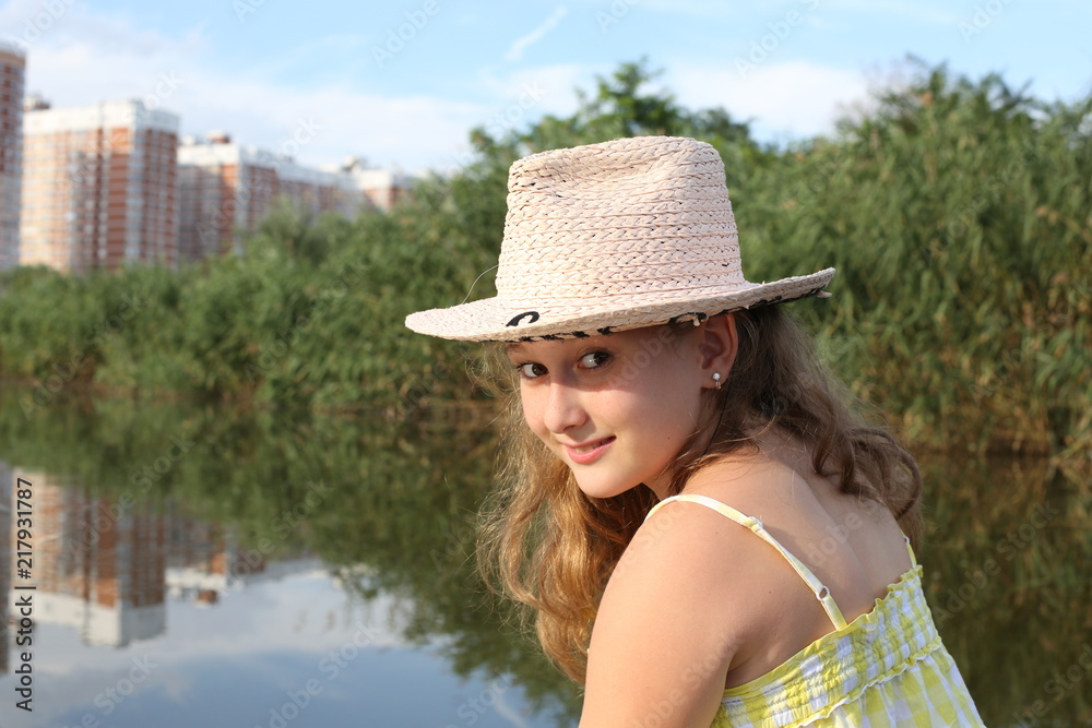 portrait happy young active pretty girl with long hair in a hat in a boat in the middle of the lake