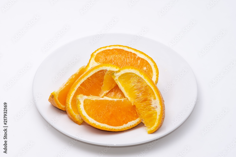 Pile of fresh sliced oranges on white plate with white background and room for copy text Pile of fresh sliced oranges on white plate with white background and room for copy text