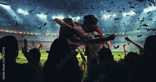 Fans celebrating the success of their favorite sports team on the stands of the professional stadium while it's snowing